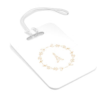 Load image into Gallery viewer, Hard, white plastic luggage tag with a graphic of the Eiffel Tower surround by a wreath of flowers printed on it in gold