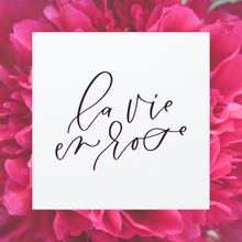 Load image into Gallery viewer, A 10" x 10" square white canvas with the phrase 'la vie en rose' printed on it in a contemporary caligraphic script: L'Abeille Française