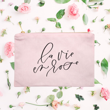 Load image into Gallery viewer, Powder-pink cotton canvas cosmetic bag with 'la vie en rose' printed on the front in black script: L'Abeille Française