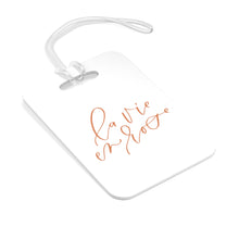 Load image into Gallery viewer, Hard, white plastic luggage tag with La Vie En Rose written on it in a rose gold script