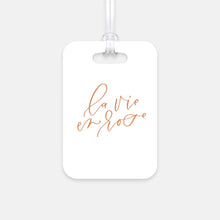 Load image into Gallery viewer, Hard, white plastic luggage tag with La Vie En Rose written on it in a rose gold script