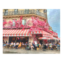 Load image into Gallery viewer, A 252-piece 14" × 11" jigsaw puzzle of the Restaurant La Favorite in Paris bedecked in pink and white striped awnings and festooned with an abundance of pink flowers.