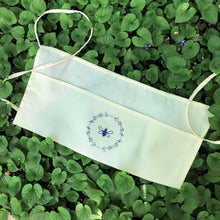 Load image into Gallery viewer, Natural-coloured garden apron with three pockets, two ties and a lavender bee and wreath graphic
