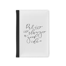 Load image into Gallery viewer, The white front cover of a faux leather passport holder is printed with a black script saying 'Paris is always a good idea' and has a black spine.