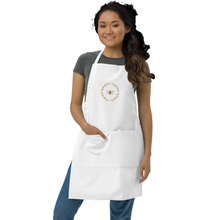 Load image into Gallery viewer, A white canvas apron with a graphic of a bumble bee surrounded by a wreath of flowers embroidered in gold thread: L'Abeille Française