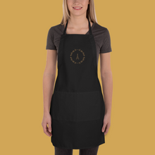 Load image into Gallery viewer, A black canvas apron with a graphic of the Eiffel Tower surrounded by a wreath of flowers embroidered in gold thread: L'Abeille Française