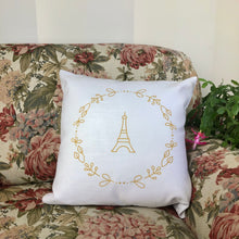 Load image into Gallery viewer, Square, white cushion with a gold graphic of the Eiffel Tower surrounded by a wreath of flowers: L'Abeille Française