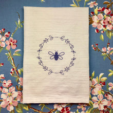 Load image into Gallery viewer, A natural coloured flour-bag cotton tea towel printed with a lavender Bee surrounded by a wreath of flowers graphic: L'Abeille Française