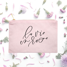 Load image into Gallery viewer, Powder-pink cotton canvas cosmetic bag with 'la vie en rose' printed on the front in black script: L'Abeille Française