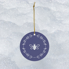 Load image into Gallery viewer, Glossy, round, lavender-coloured ceramic ornament with a white bee and wreath motif