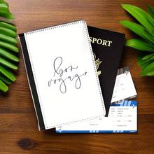 Load image into Gallery viewer, The white front cover of a faux leather passport holder is printed with a lavender coloured script saying &#39;bon voyage&#39; and has a black spine.