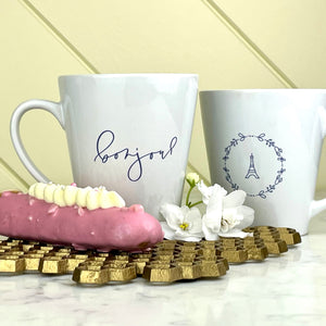 This white latte mug comes with two lavender coloured graphics printed on it, with "bonjour" one one side and the Effiel Tower surrounded by a wreath of flowers on the other: L'Abeille Française