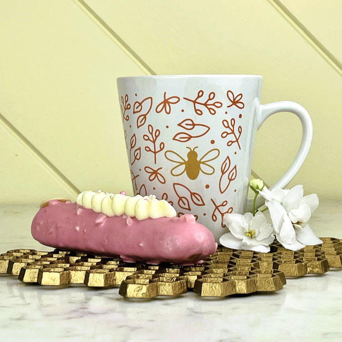 Busy Bee Latte Mug - wrap-around graphic of a gold bee surrounded by rose gold flowers on a white latte mug: Boutique L'Abeille Française
