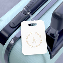 Load image into Gallery viewer, Hard, white plastic luggage tag with a graphic of the Eiffel Tower surround by a wreath of flowers printed on it in gold