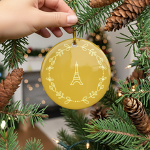 Load image into Gallery viewer, Yellow ornament with Eiffel Tower design being hung on a Christmas tree.