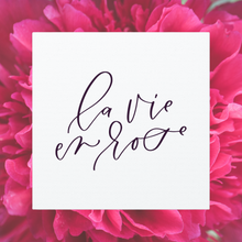 Load image into Gallery viewer, A 10&quot; x 10&quot; square white canvas with the phrase &#39;la vie en rose&#39; printed on it in a contemporary caligraphic script: L&#39;Abeille Française