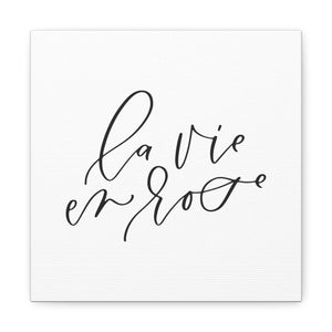 A 10" x 10" square white canvas with the phrase 'la vie en rose' printed on it in a contemporary caligraphic script: L'Abeille Française