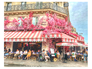 A 252-piece 14" × 11" jigsaw puzzle of the Restaurant La Favorite in Paris bedecked in pink and white striped awnings and festooned with an abundance of pink flowers.
