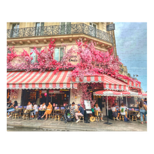 Load image into Gallery viewer, A 252-piece 14&quot; × 11&quot; jigsaw puzzle of the Restaurant La Favorite in Paris bedecked in pink and white striped awnings and festooned with an abundance of pink flowers.