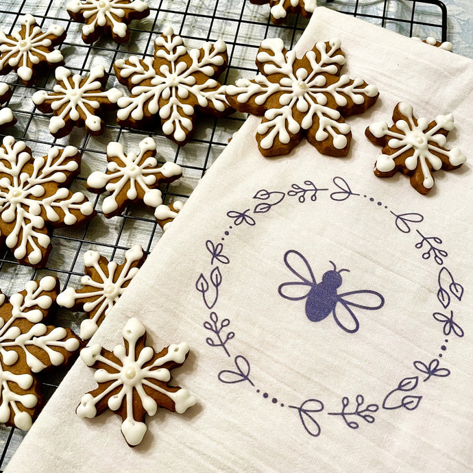 A natural coloured flour-bag cotton tea towel printed with a lavender Bee surrounded by a wreath of flowers graphic: L'Abeille Française