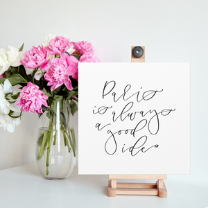 A 10" x 10" square white canvas with the phrase 'Paris is always a good idea' printed on it in a contemporary caligraphic script: L'Abeille Française