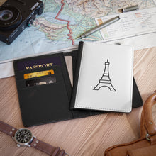 Load image into Gallery viewer, The white front cover of a faux leather passport cover is printed with a graphic of the Eiffel Tower in black and has a black spine.