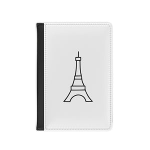 The white front cover of a faux leather passport cover is printed with a graphic of the Eiffel Tower in black and has a black spine.