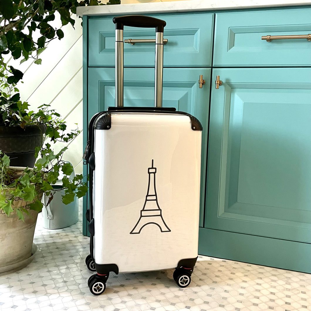 Hard-shell carry-on suitcase with black Eiffel Tower graphic on white background is accented by black trim, back, wheels and telescoping handle: Boutique L'Abeille Française