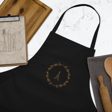 Load image into Gallery viewer, Bib of a black canvas apron with a graphic of the Eiffel Tower surrounded by a wreath of flowers embroidered in gold thread: L&#39;Abeille Française