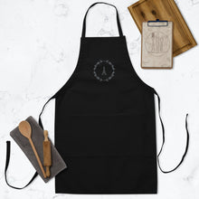 Load image into Gallery viewer, A black canvas apron with a graphic of the Eiffel Tower surrounded by a wreath of flowers embroidered in silver thread: L&#39;Abeille Française
