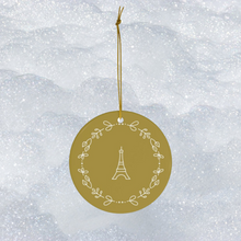 Load image into Gallery viewer, Glossy, round, gold-coloured ceramic ornament with a lighter gold-toned Eiffel Tower and wreath motif