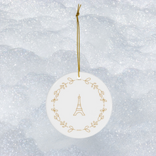 Load image into Gallery viewer, Glossy, round, white ceramic ornament decorated with a gold-toned Eiffel Tower and wreath motif
