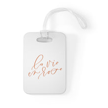 Load image into Gallery viewer, Hard, white plastic luggage tag with La Vie En Rose written on it in a rose gold script
