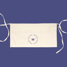 Load image into Gallery viewer, Natural-coloured garden apron with three pockets, two ties and a lavender bee and wreath graphic