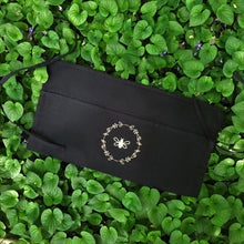 Load image into Gallery viewer, Black garden apron with three pockets, two ties and a gold bee and wreath graphic