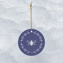 Load image into Gallery viewer, Glossy, round, lavender-coloured ceramic ornament with a white bee and wreath motif 