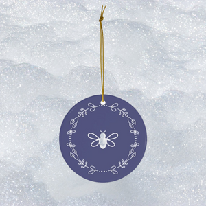 Glossy, round, lavender-coloured ceramic ornament with a white bee and wreath motif 