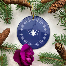 Load image into Gallery viewer, Glossy, round, lavender-coloured ceramic ornament with a white bee and wreath motif